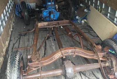 An antique car chassis secured inside the moving truck